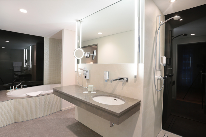 Modernes Hotelbad mit Dusche, Badewanne und großem Spiegel im Kongresshotel Potsdam.