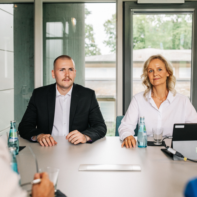 Zwei Personen in Office-Kleidung an einem Tisch.
