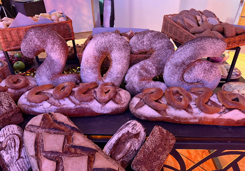 Große Brotinstallation mit den Zahlen „2026“, aus Mehl bestäubten Broten und Brezeln, dekorativ auf einem Buffet angerichtet.