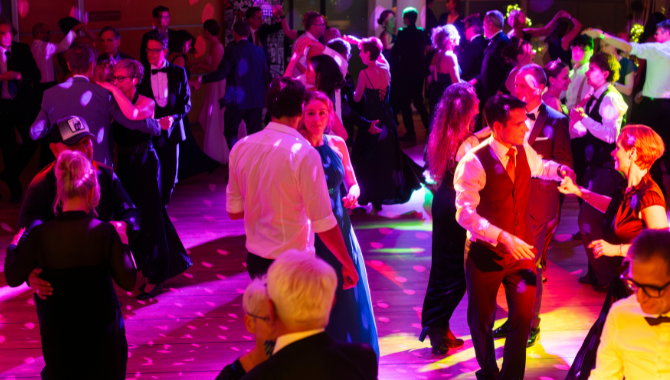 Tanzende Gäste auf einer bunten, lebhaften Tanzfläche mit farbigen Lichteffekten.
