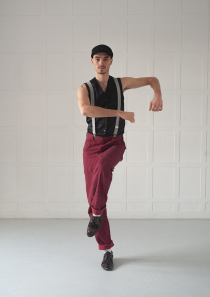 Tänzer in roter Hose posiert in hellem Studio.