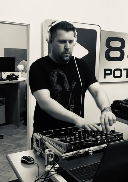 DJ mit Kopfhörern arbeitet an einem Mischpult in einem Innenraum.