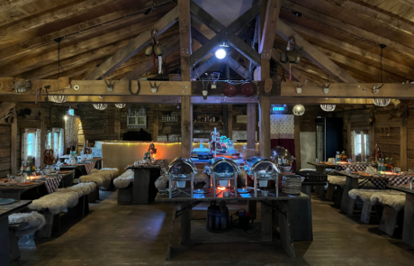 Kongresshotel-Potsdam-Gipfel-Stüberl Rustikale Holzhütte mit gedeckten Tischen, Sitzbänken und Buffet für eine Veranstaltung.