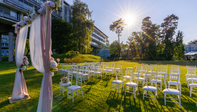 Freie Trauung auf der Wiese des Kongresshotels Potsdam mit weißen Stühlen und Traubogen.