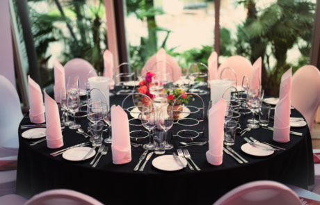 Kongresshotel-Potsdam-Zeppelinrestaurant-Tischdeko Festlich gedeckter runder Tisch mit rosa Servietten, Gläsern und Blumendekoration.